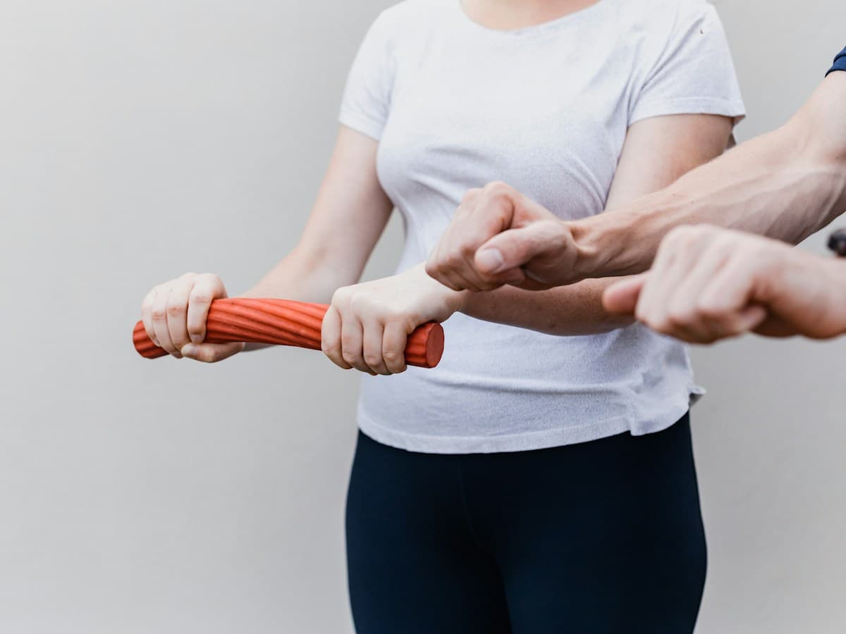 Physiotherapist assisting a patient with shoulder resistance training in clinic